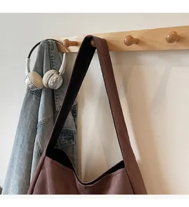 Macro detail of dark brown suede tote bag featuring a wide comfortable shoulder strap