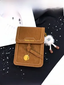 Detail of brown litchi pattern leather phone bag with plush charm and gold pendant