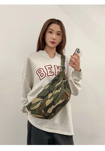 Close-up of camouflage crossbody chest bag with orange fashion label on a model