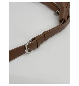 Detail of caramel brown lychee leather strap with silver round buckle and neat stitching