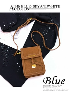 Detail of a brown small crossbody bag with a round gold pendant and smooth texture