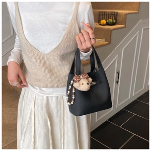 Détail d'un sac seau en cuir grainé noir avec fermoir argenté et breloque ours