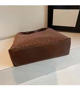 Détail du sac cabas léopard montrant la texture suédée et la base en cuir renforcée