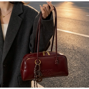 Detail of burgundy bowling bag with embossed lettering and braided charm on street setting