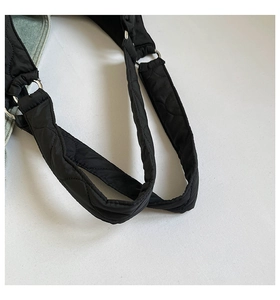 Detail der schwarzen Stepptasche mit silbernen Ringen und gepolsterten Trägern