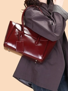 Elegant burgundy patent leather tote bag with double handles and metallic feet studs