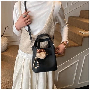 Vue détaillée du sac seau noir en cuir grainé avec pendentif ours en peluche mignon