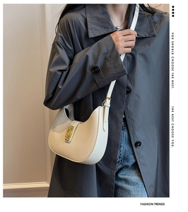 Detailed view of a white hobo bag with gold hardware worn by a model in a minimal setting