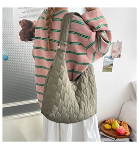 Gesteppte grüne Hobo-Tasche mit Rautenmuster und Silberringen an der Schulter getragen