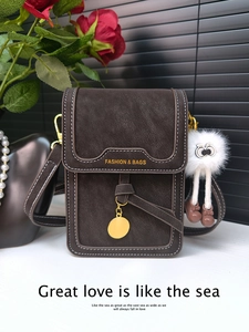 Detail of dark brown leather phone bag with white stitching and plush charm