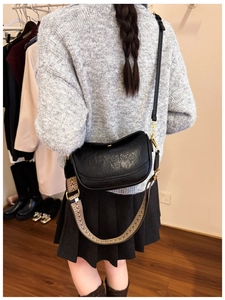 Détail d'un sac bandoulière demi-lune noir avec texture vintage et large sangle tissée