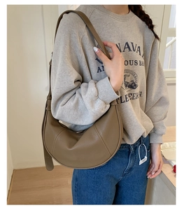 Detailed texture of brown pebble leather on a crescent bag with a wide shoulder strap