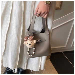 Détail du sac seau en cuir taupe avec fermoir argenté et charmant ourson en peluche