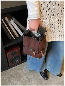 Détail du sac seau en daim marron avec surpiqûres blanches et pendentif peluche décoratif