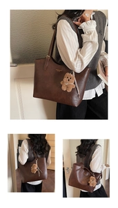 Detail of dark brown leather tote bag with embossed text and plush bear charm accessory