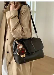 Detail der großen schwarzen Ledertasche mit Bärenanhänger und doppelten Henkeln