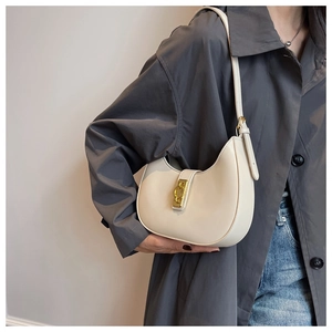 Detail of beige crescent underarm bag featuring a metallic gold interlocking buckle