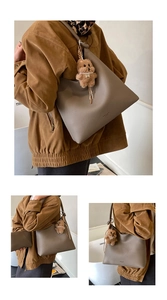Détail du cabas taupe avec cuir texture litchi et un joli pendentif en forme d'ours