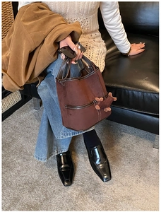 Détail du sac seau en daim marron foncé avec bordures en cuir et breloque en peluche