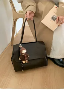 Detail der dunkelbraunen matten Ledertasche mit süßem Teddybär-Anhänger am Riemen