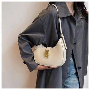 Chic cream white crescent underarm bag with gold ring buckle shown on gray coat