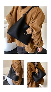 Détail du sac hobo en cuir grainé noir avec un adorable pendentif ours en peluche marron