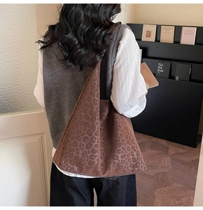 Détail d'un grand sac cabas imprimé léopard en daim porté à l'épaule par un mannequin