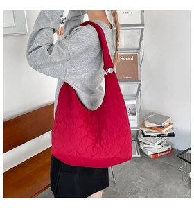 Detail einer roten gesteppten Tragetasche aus Nylon mit Silberringen und Rautensteppmuster