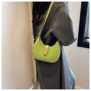 Detail view of bright green crescent underarm bag with gold twist lock on trench coat