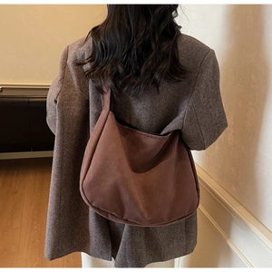 Detail of a large brown suede tote bag styled with a vintage herringbone blazer
