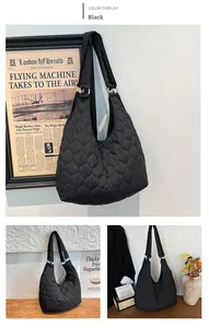 Détail du sac fourre-tout noir matelassé avec coutures en losange et anneaux argentés