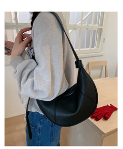 Detail of black crescent shoulder bag in pebble leather worn by a model in a casual setting