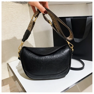 Détail du sac croissant noir avec texture cuir vintage et bandoulière tissée géométrique