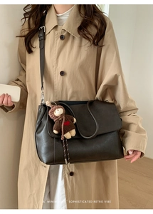 Dunkelbraune matte Tragetasche mit beigem Trenchcoat und Bärenanhänger gestylt