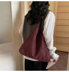 Détail du grand sac hobo bordeaux à motif léopard porté comme accessoire d'épaule