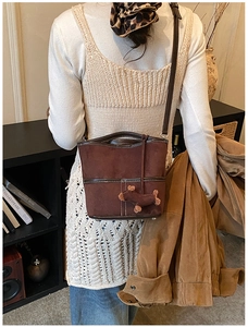 Détail du sac seau rétro en daim marron avec surpiqûres et pendentif en peluche