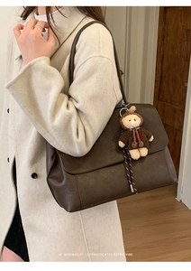 Details der dunkelbraunen Retro-Schultertasche mit Plüschbär-Anhänger und Klappverschluss