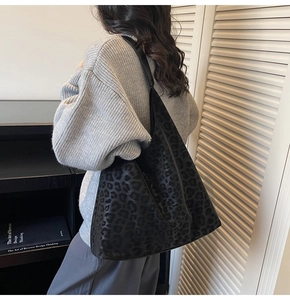 Sac hobo chic à imprimé léopard noir avec design spacieux et large bandoulière porté par mannequin