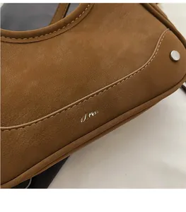Detail shot of brown leather bag texture with silver stud and MZACRAKE brand logo