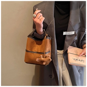 Détail du sac seau en daim marron avec bordure en cuir et breloque chien en peluche