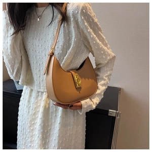 Detail of camel brown crescent underarm bag with gold metal buckle on white blouse