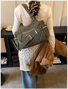 Detailed back view of army green punk tote bag with studs and belt strap on a model