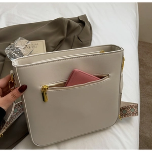 Detail of cream crossbody bag with vintage embroidered strap and internal storage view