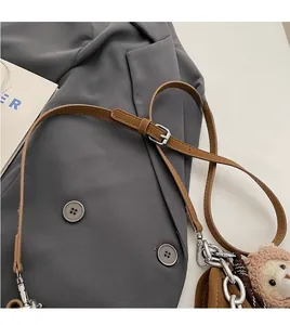 Detail of brown leather strap with silver buckle and cute bear plush pendant