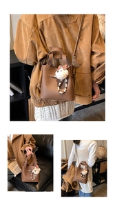 Détail d'un sac seau en cuir marron avec un joli pendentif en forme d'ours blanc
