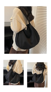 Detailed view of black hobo shoulder bag with wide strap and spacious crescent design