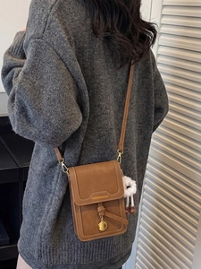 Vintage brown leather crossbody phone bag with adjustable strap and plush charm