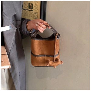 Vue détaillée du sac seau vintage en daim marron avec garniture en cuir et charme peluche