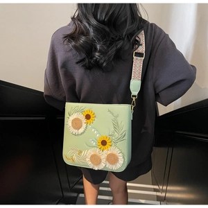Detail of light green floral bag with sunflower embroidery and ethnic woven shoulder strap