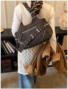 Retro messenger bucket bag with metal rivets and multi-zipper pockets in a lifestyle scene